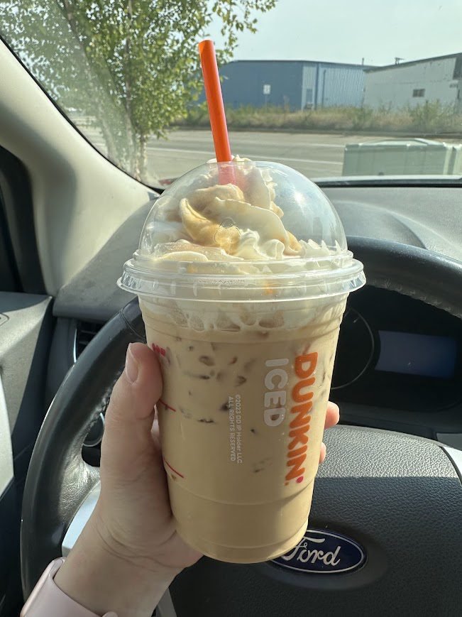 Dunkin iced PSL with whipped cream and orange straw, dome lid